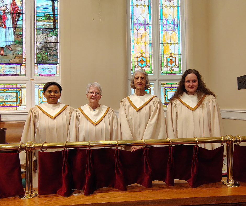 Four Chancel Choir members in white robes with gold stoles standing behind the sanctuary rail