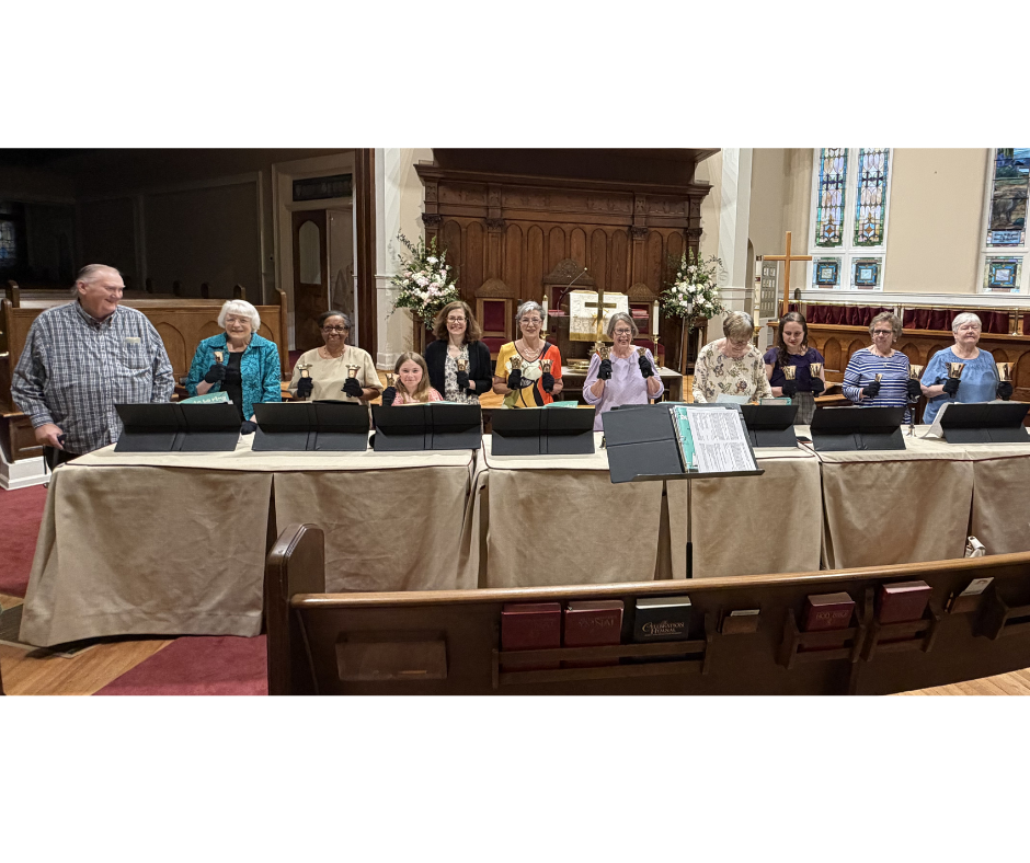 Community handbell group ringing two sets of handbells behind tables in the sanctuary