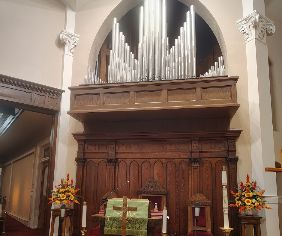 Silver pipes of the Casavant pipe organ above dark wood paneling behind the sanctuary altar